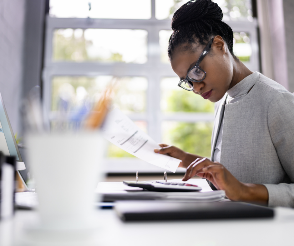 Une expert comptable Paris 15 travaillant dans son bureau, concentrée sur des documents financiers, avec une calculatrice à la main.